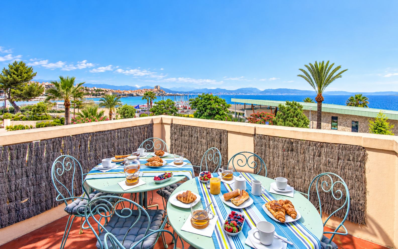 Eine Terrasse mit gedeckten Tischen mit Blick auf eine Küstenstadt und das Meer.