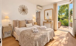 Une chambre à coucher avec un lit, des tables de chevet, un miroir et une vue sur l’extérieur.