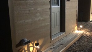 Ein Holzhaus mit Tür und kleiner Veranda.