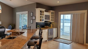 A modern kitchen with granite countertops, white cabinetry, and a built-in wine rack. - Lakefront Sunsets and Sandy Beach in Rockford, MI (ROCKFORD)