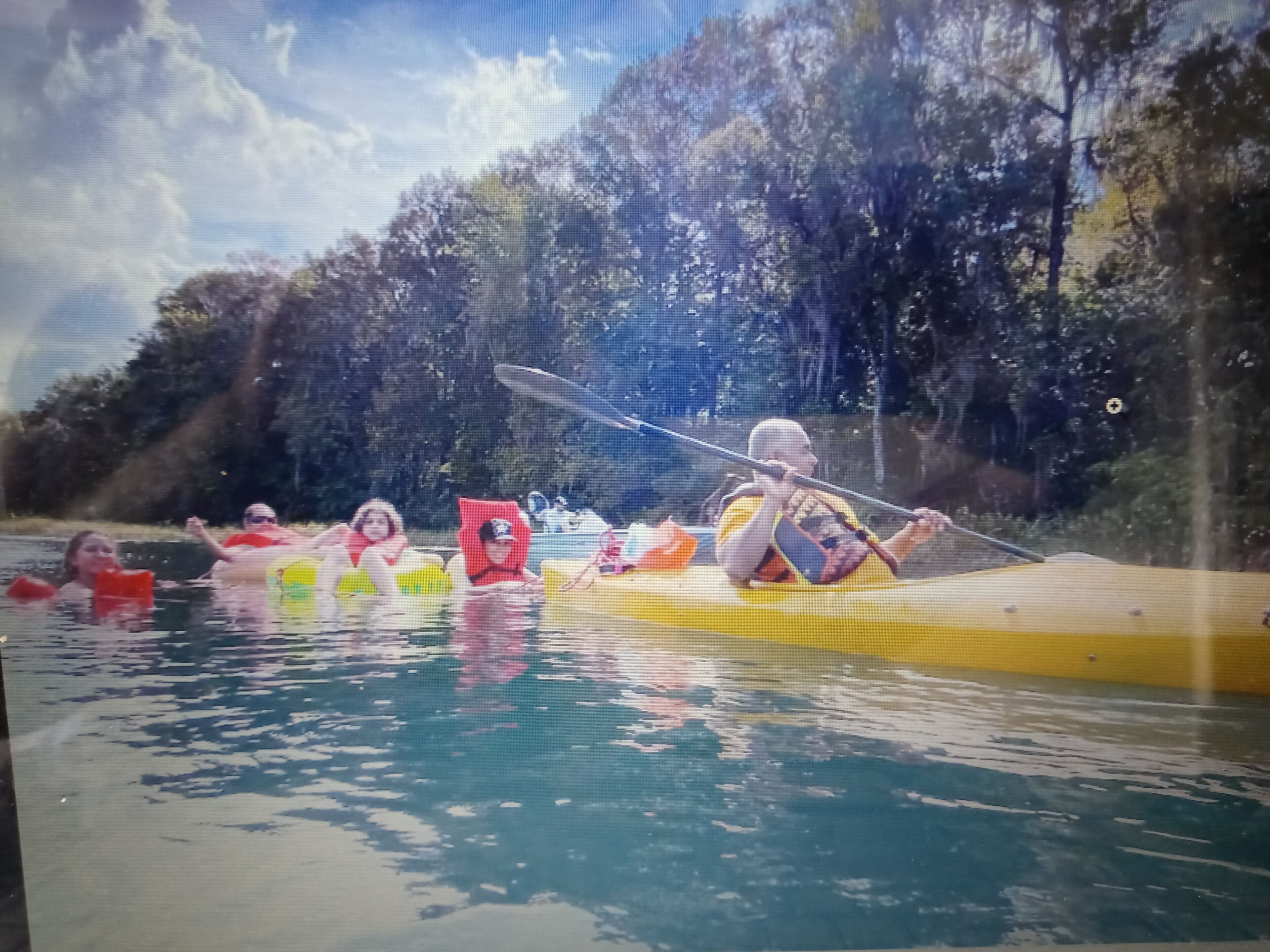 A group of people kayaking on a river surrounded by trees.