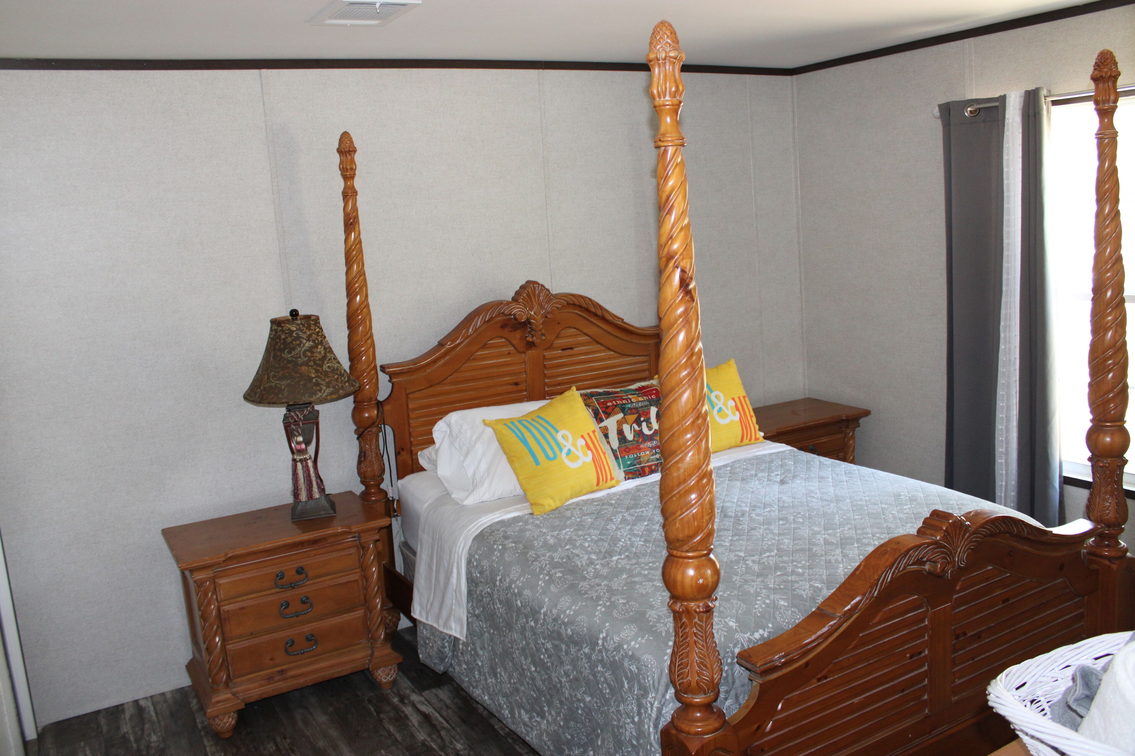 A four-poster bed with a wooden headboard, a bedside table with a lamp, and a nightstand.