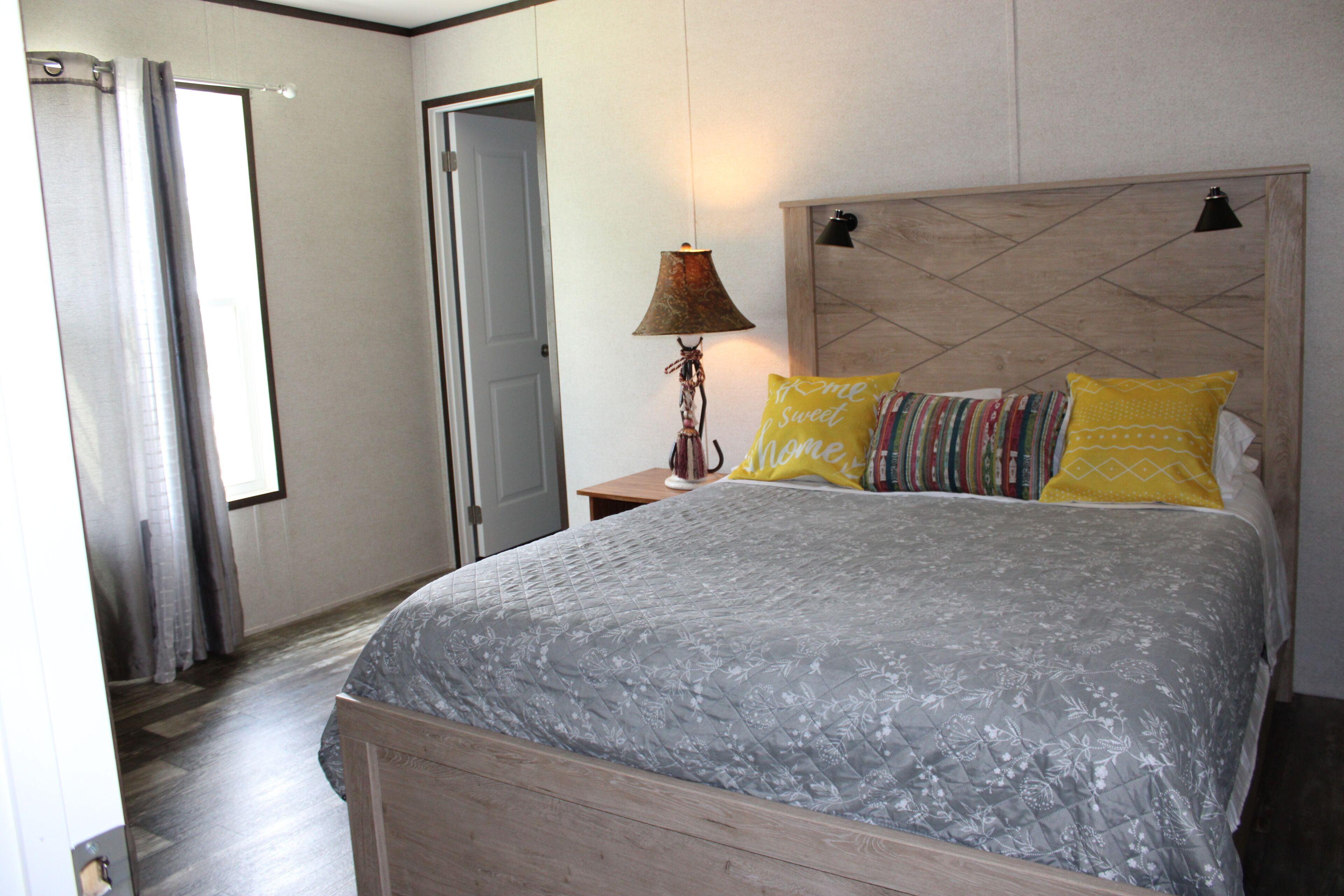 A bedroom with a bed, a nightstand, a lamp, and a door.