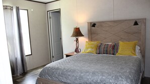 Ein Schlafzimmer mit Bett, Nachttisch, Lampe und einer Tür.