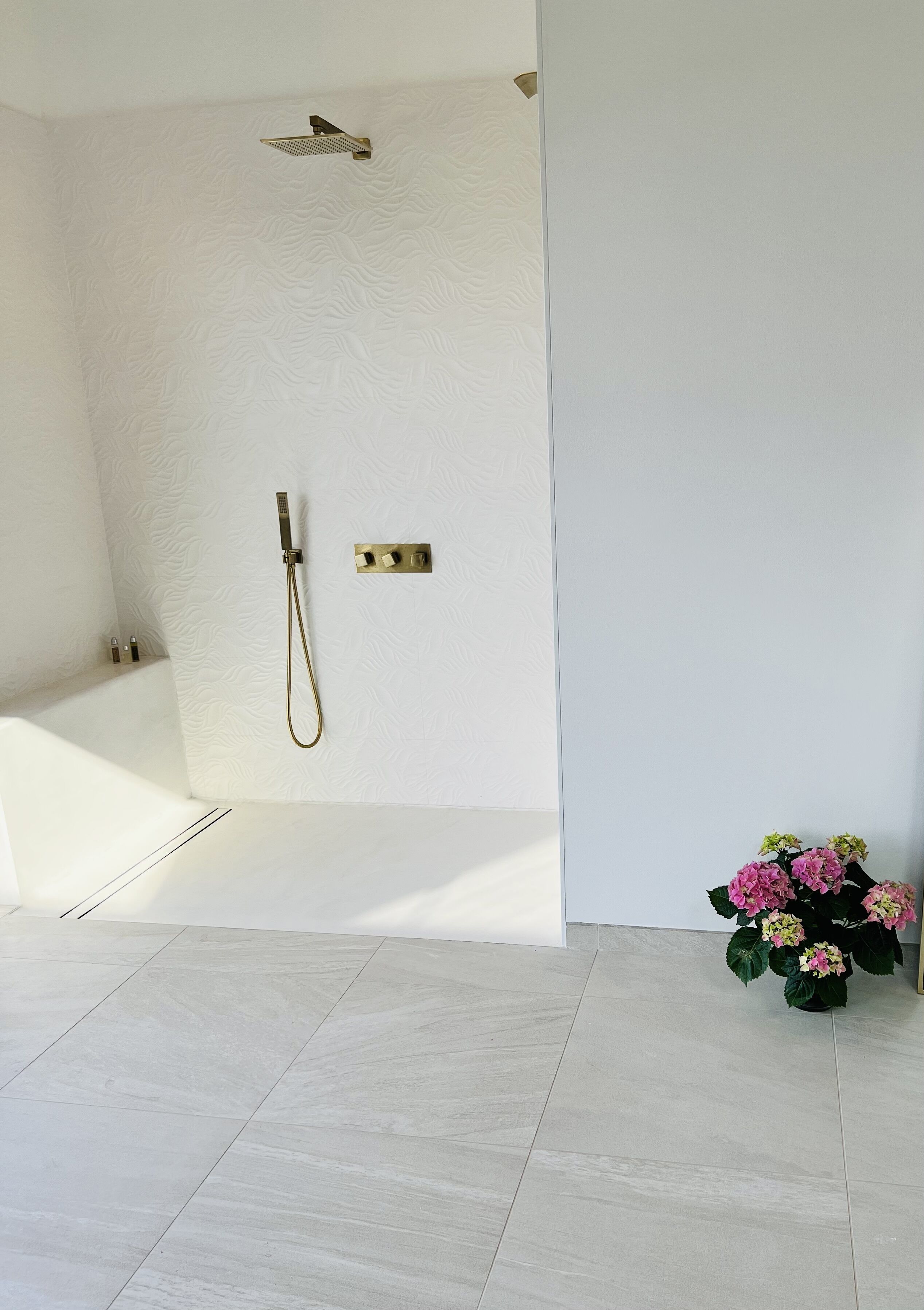 Et moderne badeværelse med bruser, badekar og en potteplante.