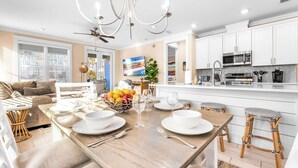 Een moderne keuken met witte kastjes, een roestvrijstalen magnetron en een eethoek met een houten tafel gedekt voor vier personen.