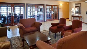 Un vestíbulo con varios sofás y sillones, un mostrador de recepción y un amplio ventanal con vistas al exterior.