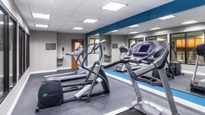 Un gimnasio con cintas de correr, una bicicleta estática y una máquina de remo.