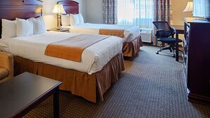 Una habitación de hotel con dos camas, un sofá, un escritorio y una silla.