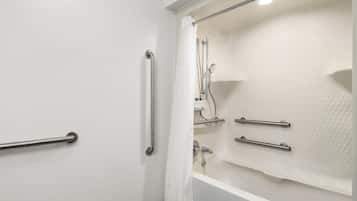 A bathroom with a bathtub, a shower, and a toilet. There are grab bars installed for safety.