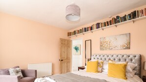 Ein Schlafzimmer mit einem großen Bett, einer Couch, einem Bücherregal und einer Tür.
