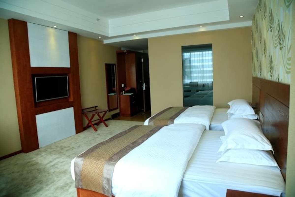 A hotel room with two beds, a TV, and a desk.