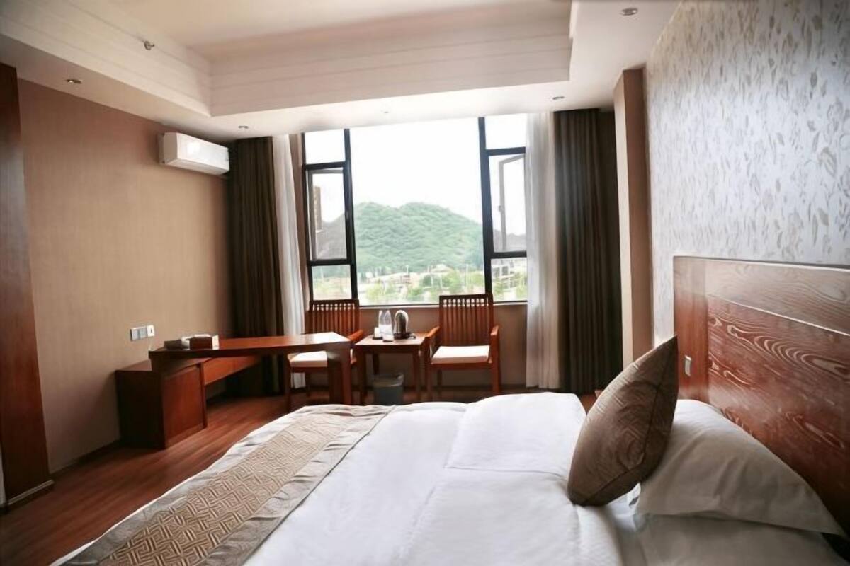 Habitación de hotel con una cama grande, un escritorio y una silla, con vistas a zonas verdes.