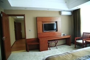 A hotel room with a bed, a desk with a television, a chair, and an air conditioning unit. - Longhuyuan Hostel (Yanshan)