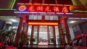 A hotel entrance with a neon sign, large glass doors, and potted plants. - Longhuyuan Hostel (Yanshan)
