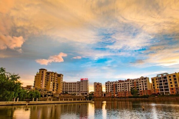 A waterfront view with multiple high-rise buildings, a calm body of water, and a clear sky. - Longhuyuan Hostel (Yanshan)