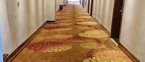 A long hallway with patterned carpet and doors on both sides.
