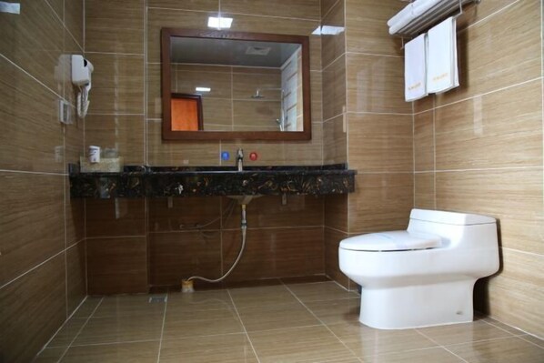 A bathroom with a toilet, a sink with a mirror, and a shower. - Longhuyuan Hostel (Yanshan)