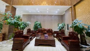 A spacious lobby with a high ceiling, marble flooring, and multiple wooden furniture pieces including sofas and a coffee table. - Longhuyuan Hostel (Yanshan)