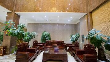 A spacious lobby with a high ceiling, large seating area, and potted plants.