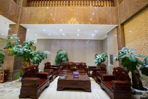 Un hall d’entrée spacieux avec un plafond haut, un grand espace salon et des plantes en pot.