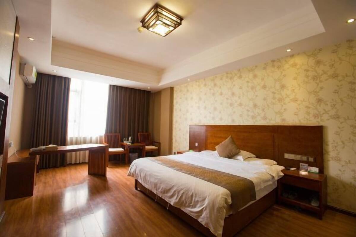 Una habitación de hotel con una cama grande, un escritorio, una silla y una mesita de noche.
