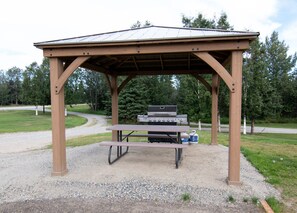 A covered picnic area with a grill and picnic table. - Alaska Frontier Inn (Delta Junction)
