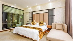 Un dormitorio con cama, sofá, baño con paredes de cristal y un ventanal grande.