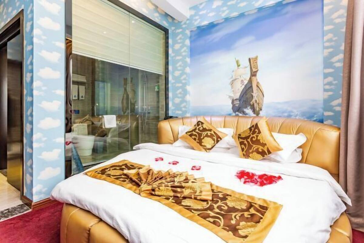A hotel room with a bed, a large window, and a wall mural.