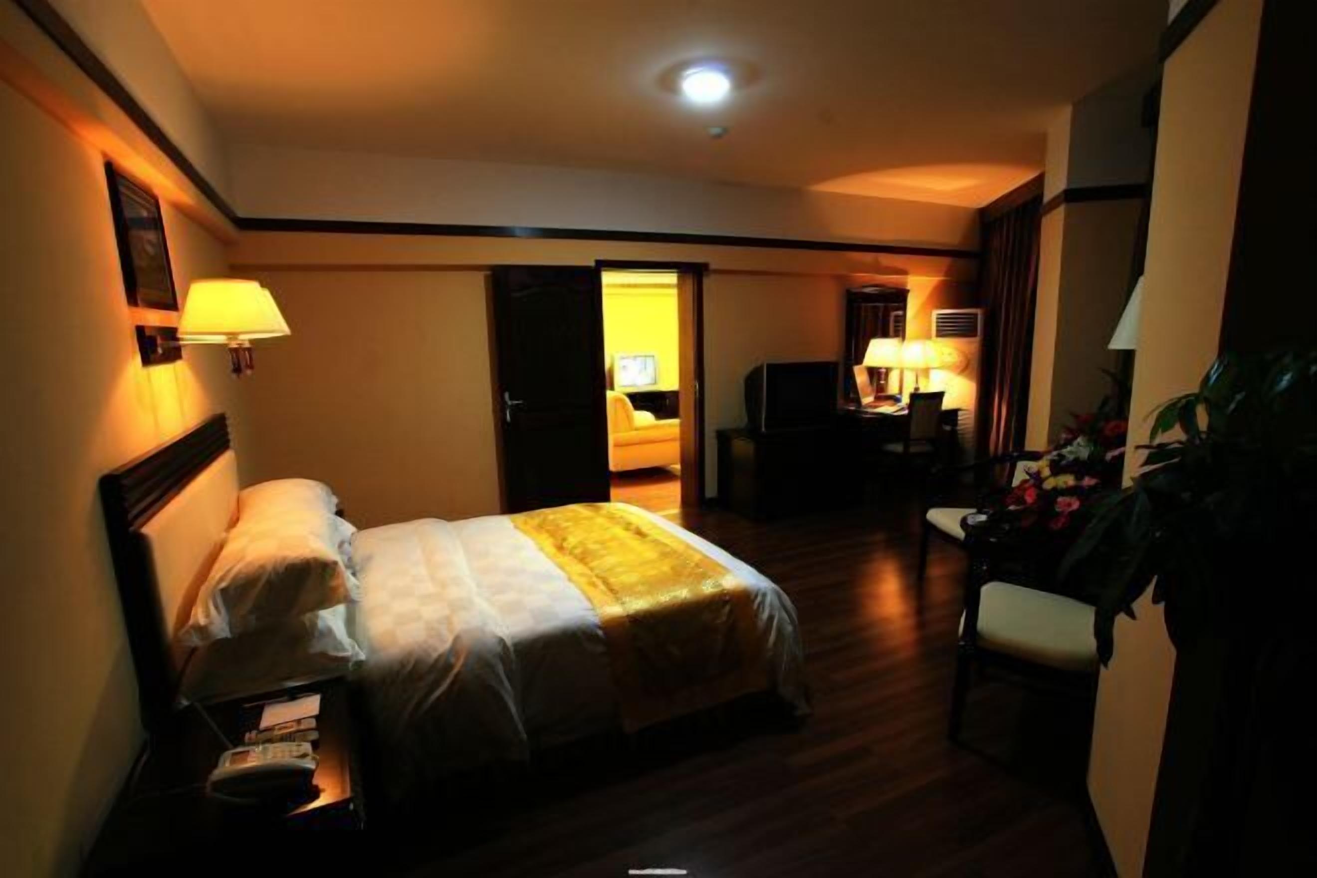 Une chambre d’hôtel comprenant un lit, une table de chevet, une lampe et un bureau avec une chaise.