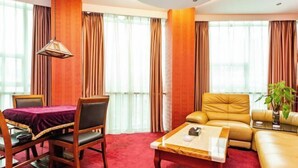 A hotel room with a dining table, a sofa, a coffee table, and a plant. - Yuanhang Hotel (Tongren)