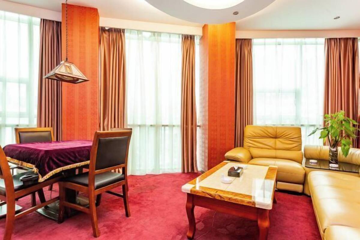 A hotel room with a dining table, a sofa, a coffee table, and a plant.