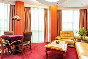 A hotel room with a dining table, a sofa, a coffee table, and a plant. - Yuanhang Hotel (Tongren)