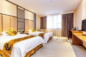 Habitación de hotel con dos camas, un escritorio y una televisión.