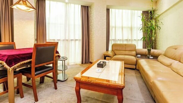 A living room with a sofa, a dining table with chairs, and a coffee table. - Yuanhang Hotel (Tongren)