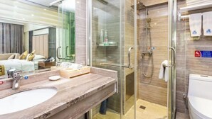 A modern bathroom with a glass-enclosed shower, a marble sink, and a visible toilet. - Yuanhang Hotel (Tongren)