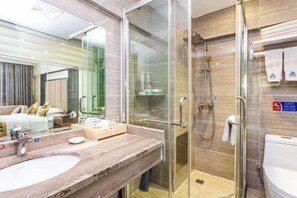Un baño moderno con ducha de vidrio, lavamanos de mármol y un inodoro a la vista.