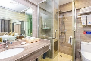 Un baño moderno con ducha de vidrio, lavamanos de mármol y un inodoro a la vista.