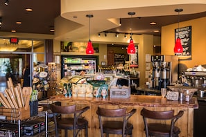 A café with a wooden bar, leather chairs, and a variety of food and drink items on display. - Honua Kai- Konea 608 Beautiful Ocean View, Large 2 bedroom on 6th floor (Lahaina)