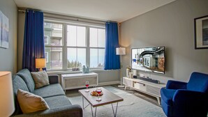 Ein modernes Wohnzimmer mit grauem Sofa, blauem Sessel, Couchtisch und flachbildschirm-Fernseher an der Wand.