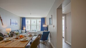 Ein Essbereich mit einem Holztisch, gedeckt für vier Personen, einem blauen Stuhl und einer Couch im Hintergrund.