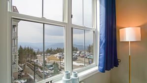Ein Zimmer mit großem Fenster und Blick auf eine verschneite Landschaft und eine Straße.