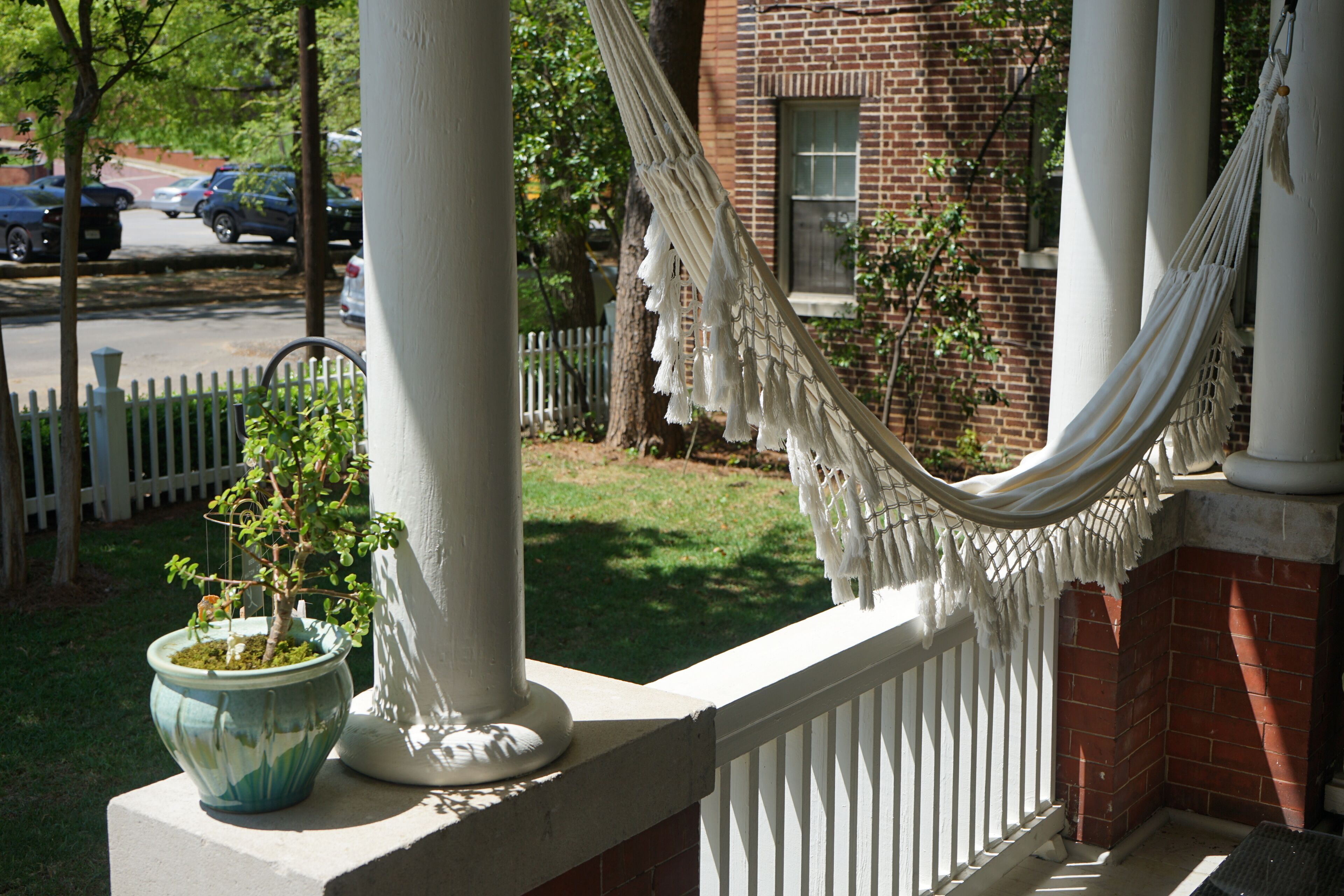 A porch with a white railing, a hammock, and a potted plant.