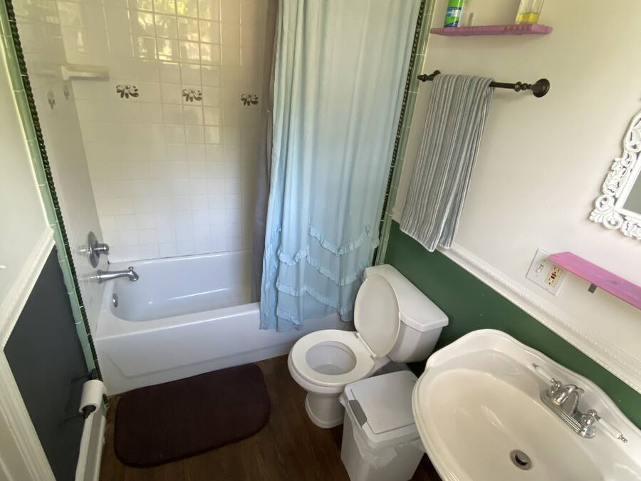A bathroom with a bathtub, toilet, sink, and shower curtain.