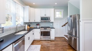 A modern kitchen with white cabinets, stainless steel appliances, and a black countertop.