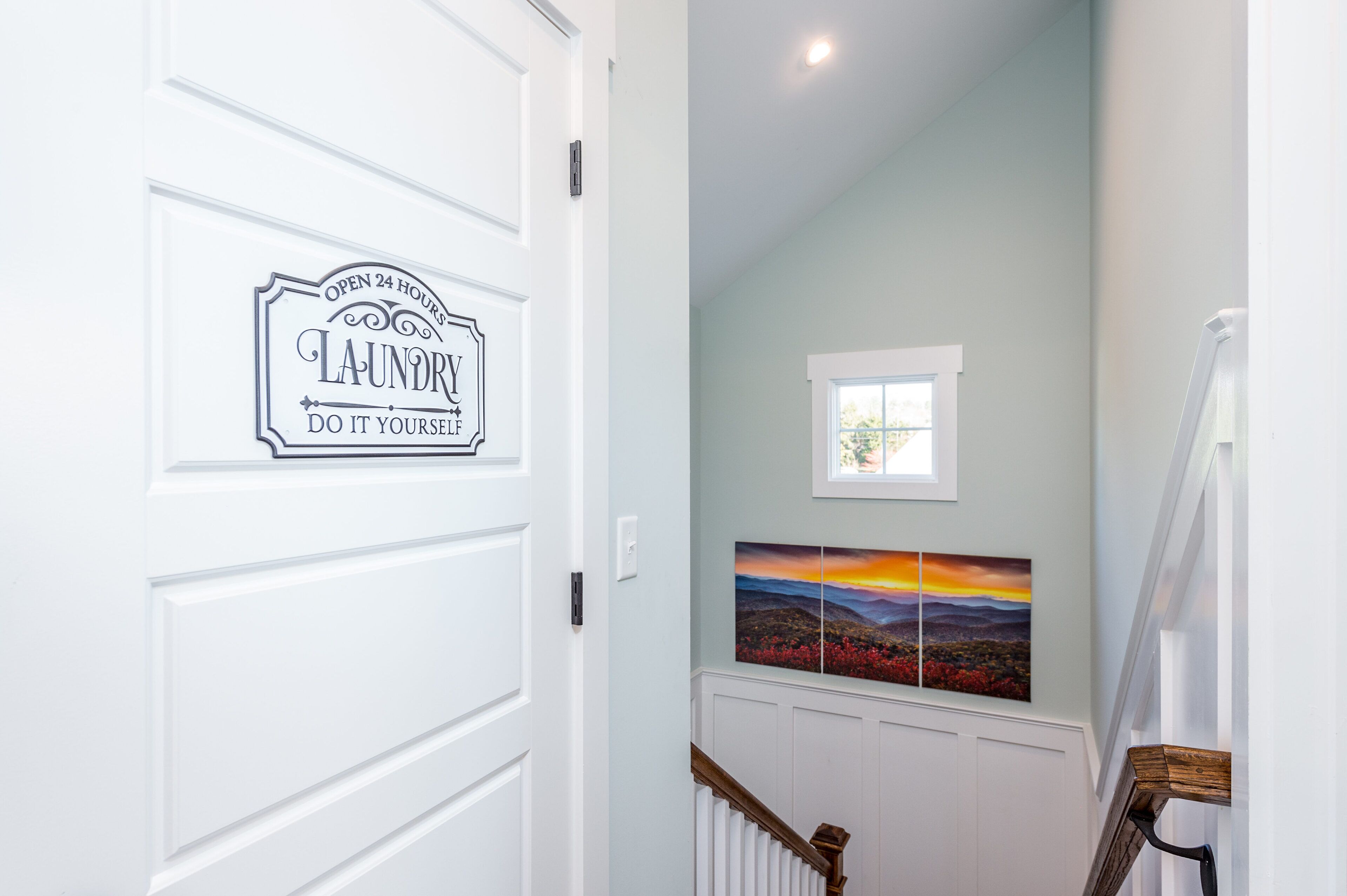 A hallway with a door labeled 'Laundry' and a painting of a landscape.
