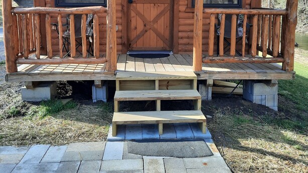 Une cabane en bois avec une véranda, une porte et une fenêtre.