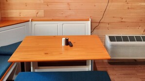 Ein Zimmer mit Holzwandverkleidung, einem Tisch mit Fernbedienung und einer weißen Klimaanlage.