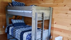 Ein Stockbett mit einer Stehle, einem Heizkörper und einer blaue und weiße Bettdecke mit Muster.