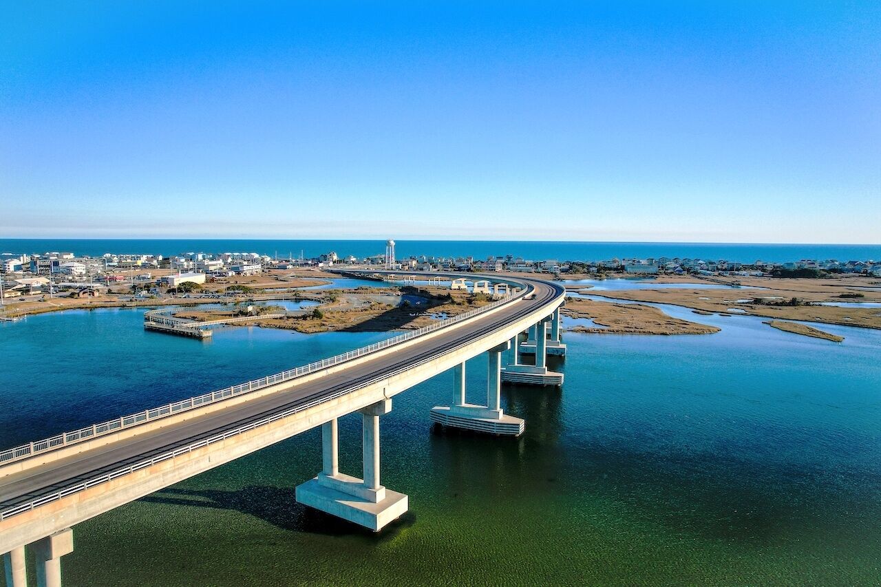 Un long pont enjambant une étendue d’eau, avec une vue sur la ville en arrière-plan.